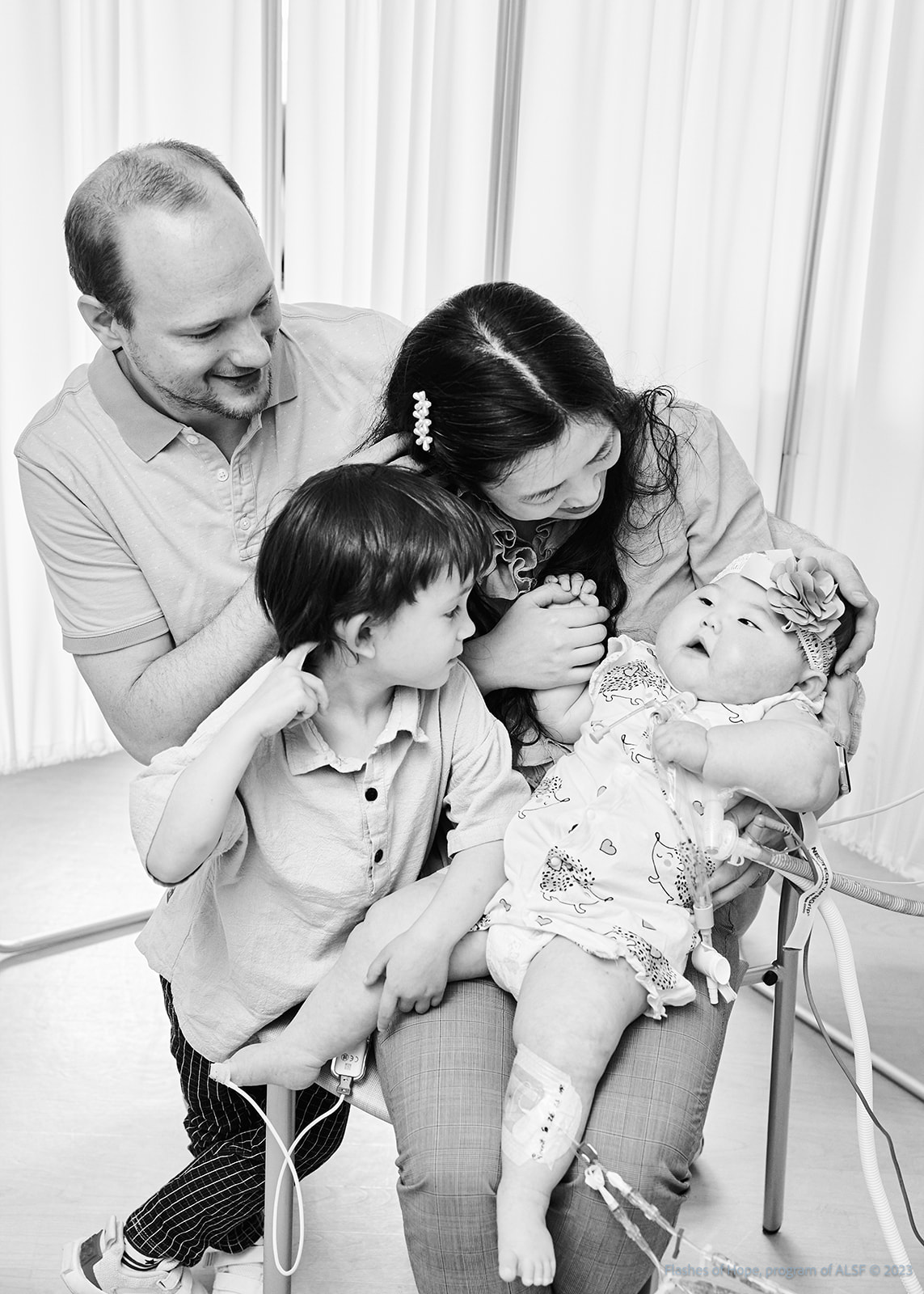 Black and white of Daddy, Mommy, Declan, and Constance sitting.  The family is looking at Constance.